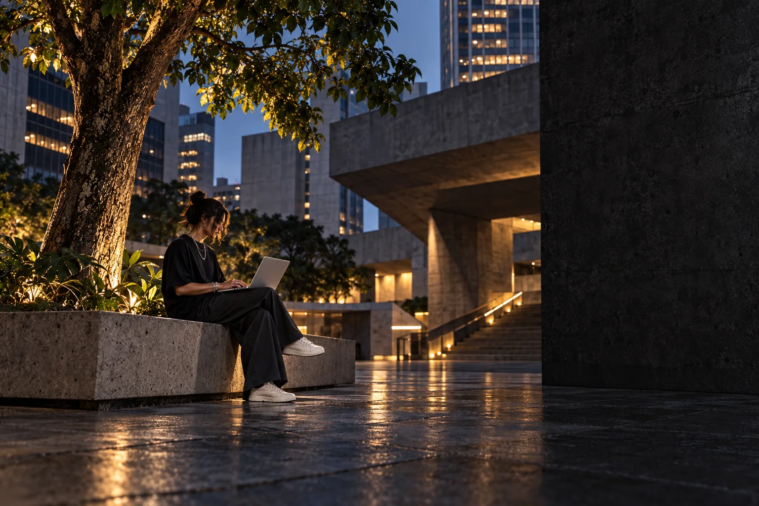 Profissional criando em um notebook, em um espaço urbano junto a uma árvore